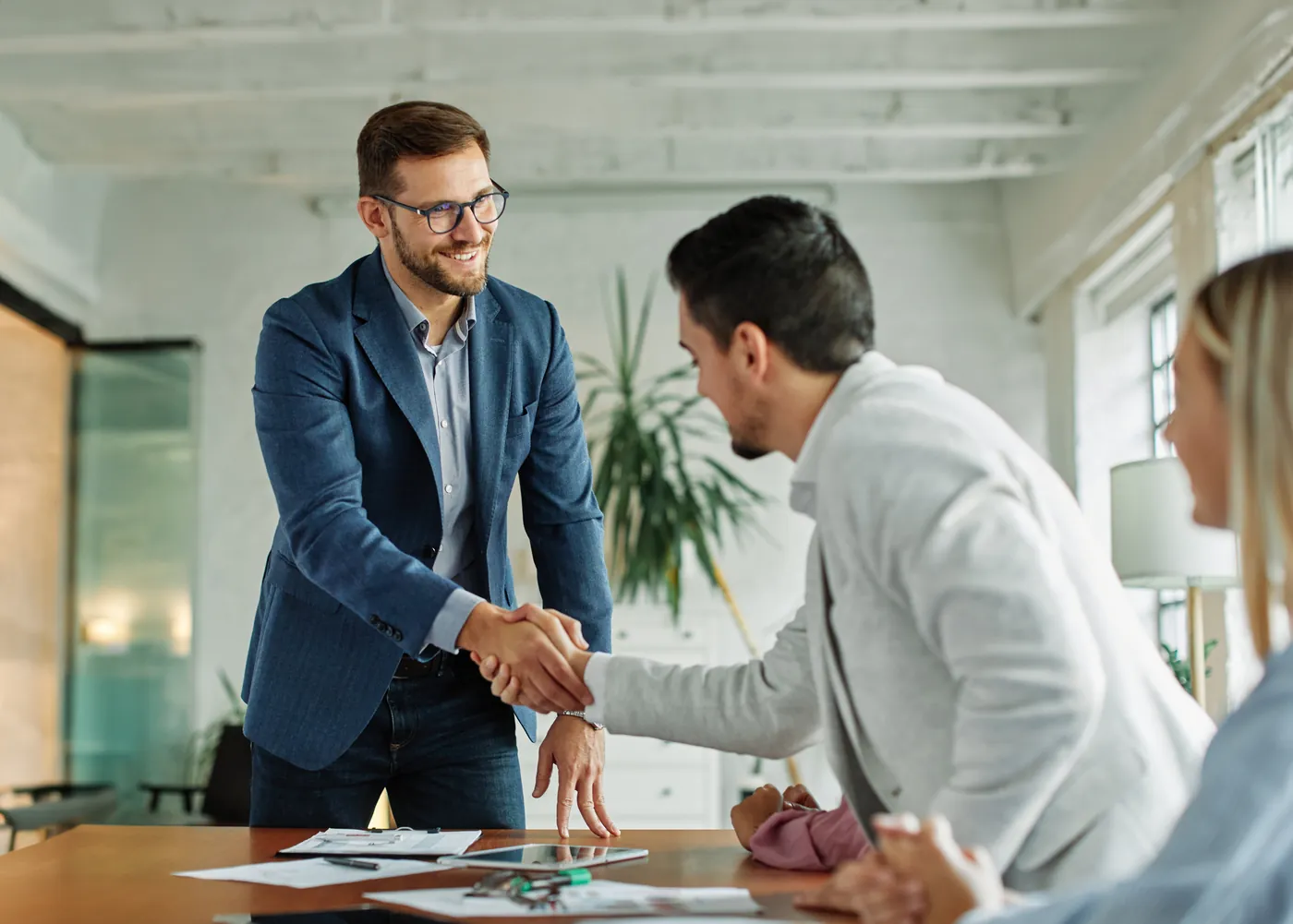 Two professionals shaking hands across a desk