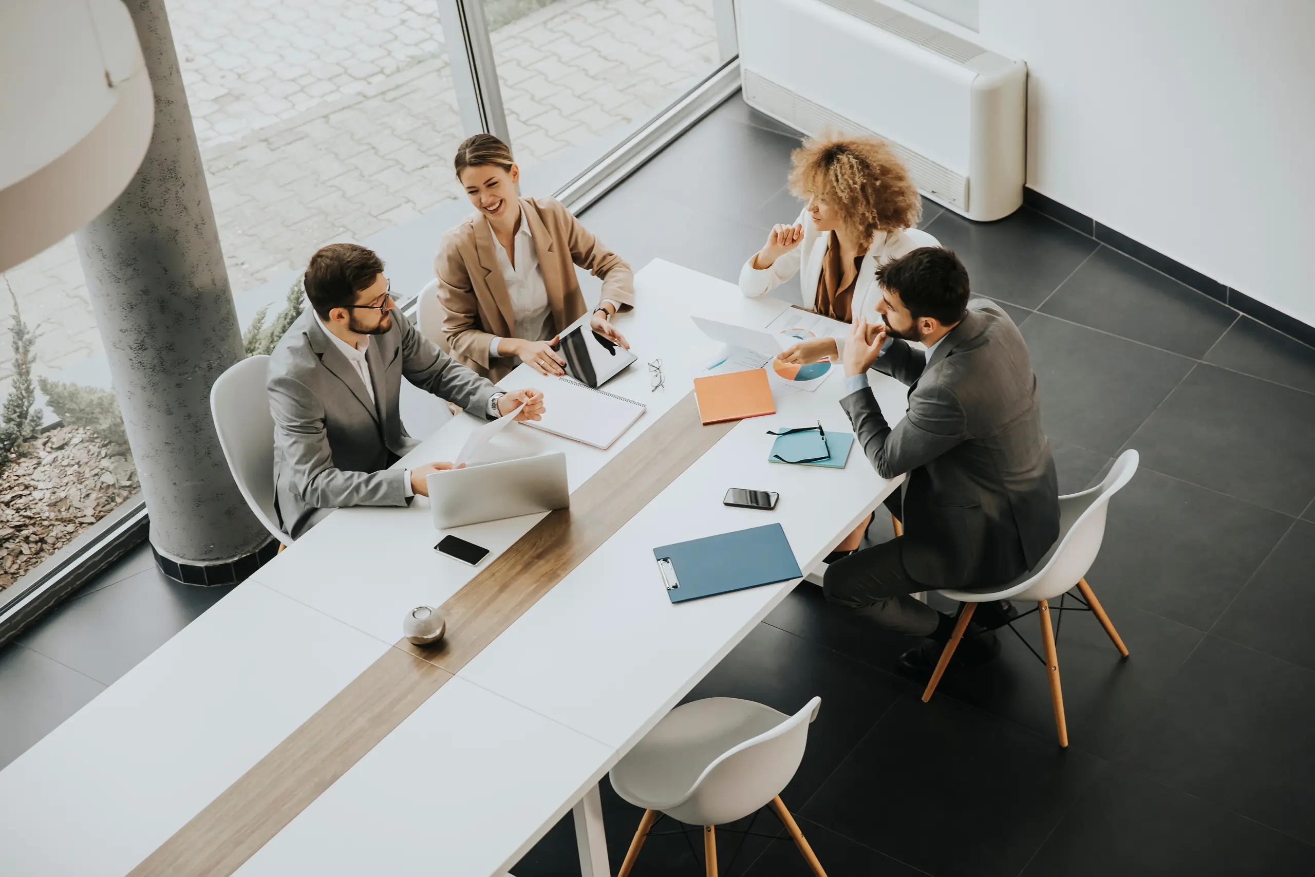 A team meeting around a boardroom table, seen from above